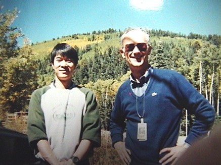 LosAlamos National Laboratory　留学中に撮影された2ショット写真。木々が生える山を背景に、左側でほほ笑む梶村先生。