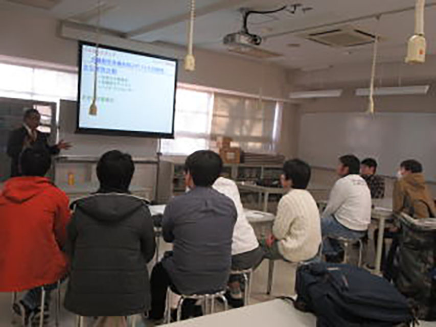 小山高専で行われた九工大進学説明会の様子。プロジェクターに映された資料と、前で説明する関係者に、熱心に話を聴く高専生たちの姿。