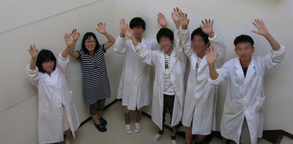 5人の研究室学生たちと、両手を上げてカメラに笑顔を向ける宇田先生。
