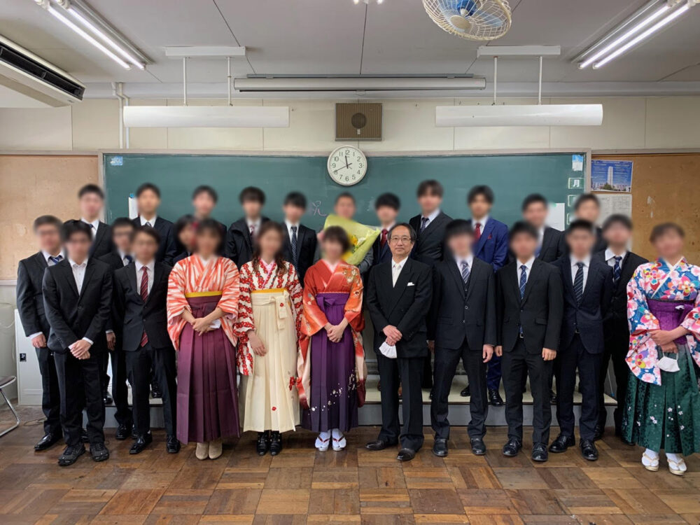 教室内での集合写真。学生はスーツや袴など正装し、笑顔でおさまっている。