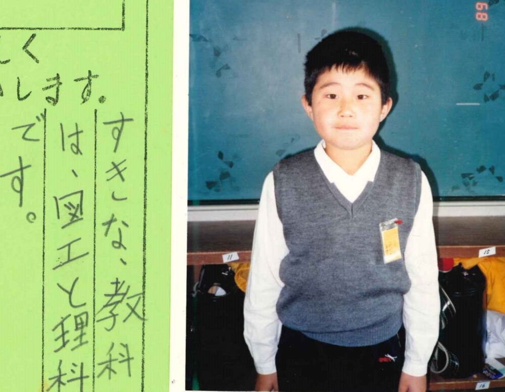 小学3年生の頃の篠崎先生。教室の黒板の前で、きをつけ　の姿勢で少しはにかんでいる。