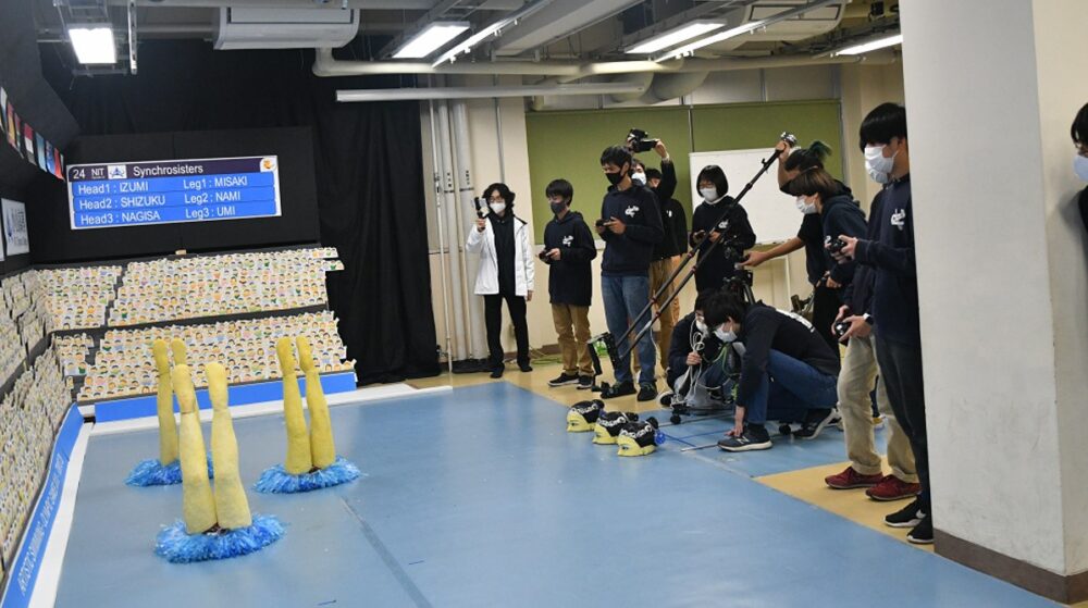 シンクロナイズドスイミングに見立てたミニチュアの会場で、足ロボットを動かし演技の練習をする学生たち。