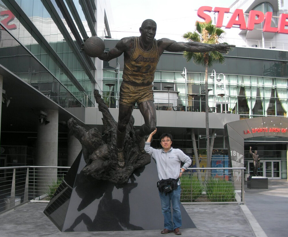有名なバスケットボール選手の像の前でポーズをとる石川先生。