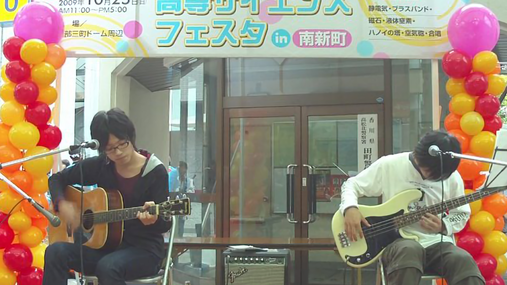 高専サイエンスフェスタ会場にて、エレキギターの友人とギターを弾く高専時代の北村先生