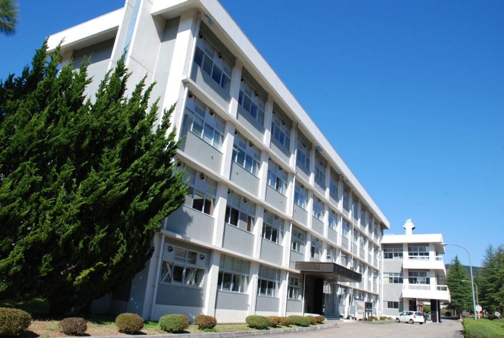 青い空、緑の木々に、4階建ての白い校舎が映える、舞鶴高専校舎