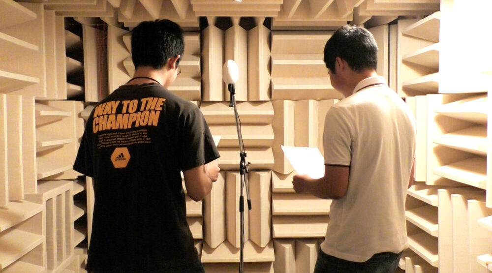 四方を凸凹した壁に囲まれた無響室で、音声の収録実験をする様子