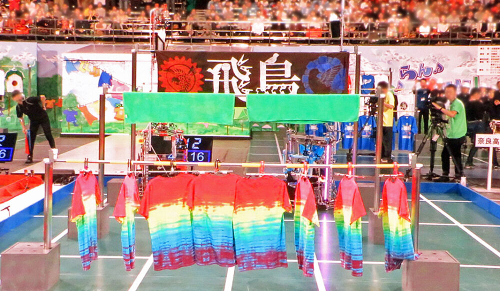 ロボコン大会に奈良高専が出場したときの様子。竿に、ハンガーで掛けた、赤青黄色のカラフルなＴシャツが10ほど干してある