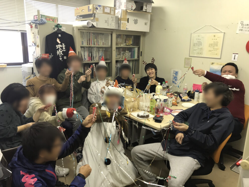 研究室の仲間たちと、被り物をしたりしてクリスマスパーティーを楽しむ岩本さんとデフィン先生