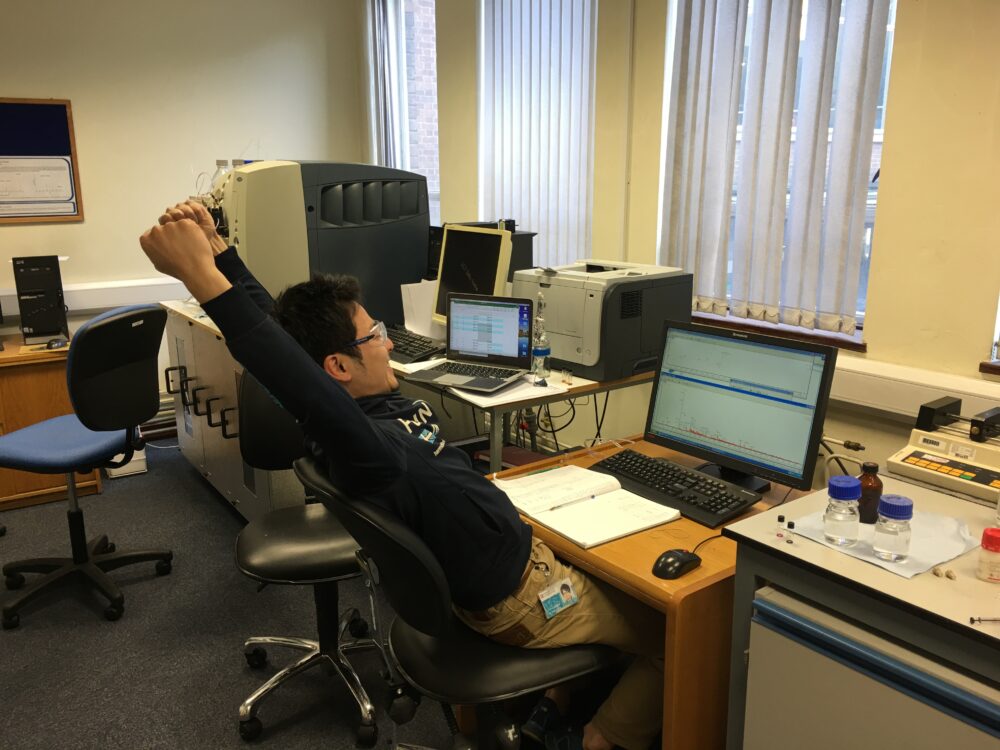 研究室の、PCデスクの前に座って、両手を突き上げて伸びている姿