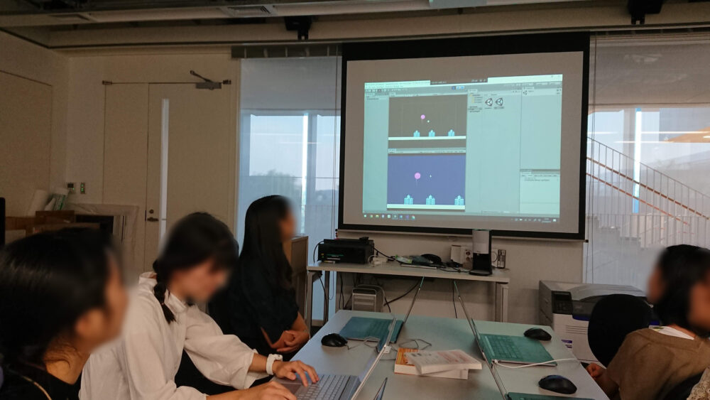 スライドに映しながらプログラミングの勉強をする学生たち
