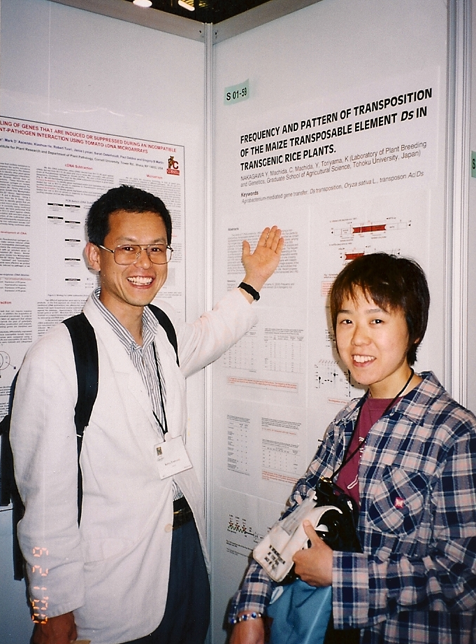 国際学会で英語のポスターを背景に、恩師と写真におさまる中川先生