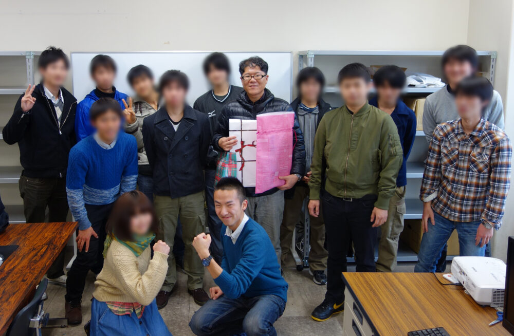 学生たちに囲まれて、祝福を受ける久保田先生