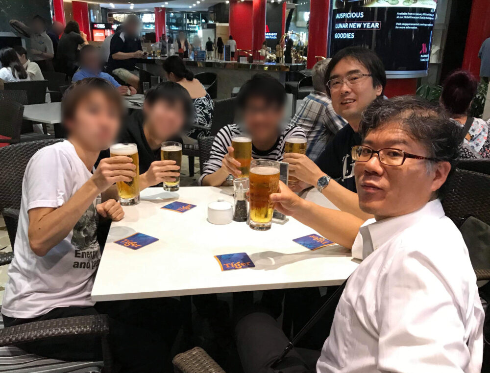 国際会議でシンガポールに行った際に、田向先生と学生らでビールで乾杯する久保田先生