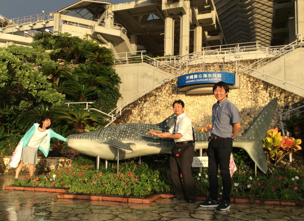 沖縄の美ら海水族館のジンベエザメのモニュメントの前で。