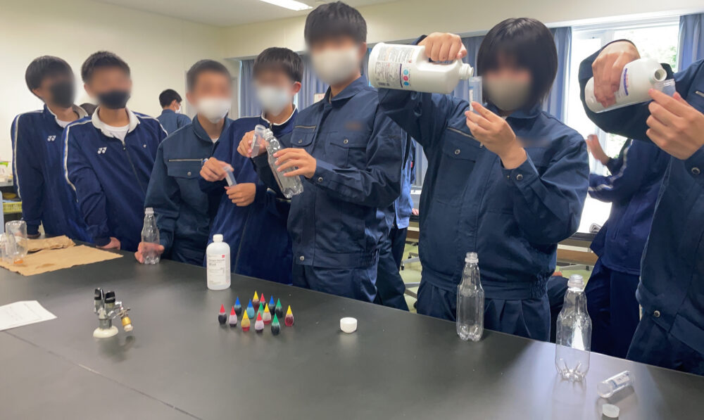 室内、理科室にて、学生たちが並び、洗剤を容器に入れている様子。