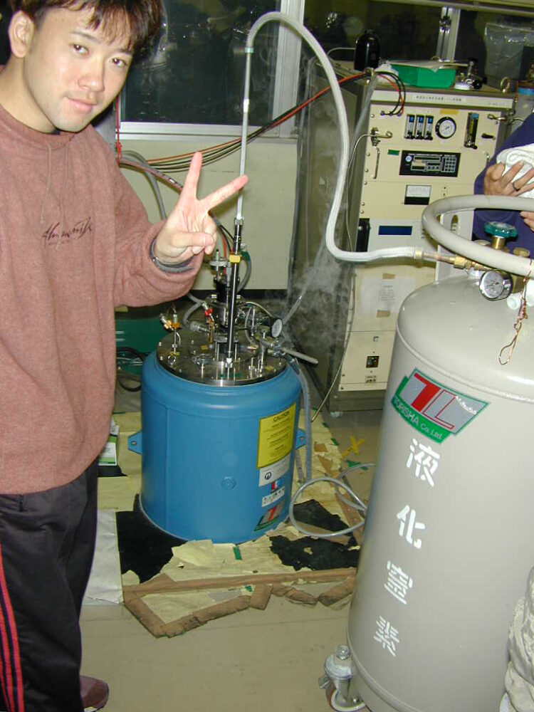 液化窒素のボンベに繋がれた機器とともに、大学院時代の稲田先生