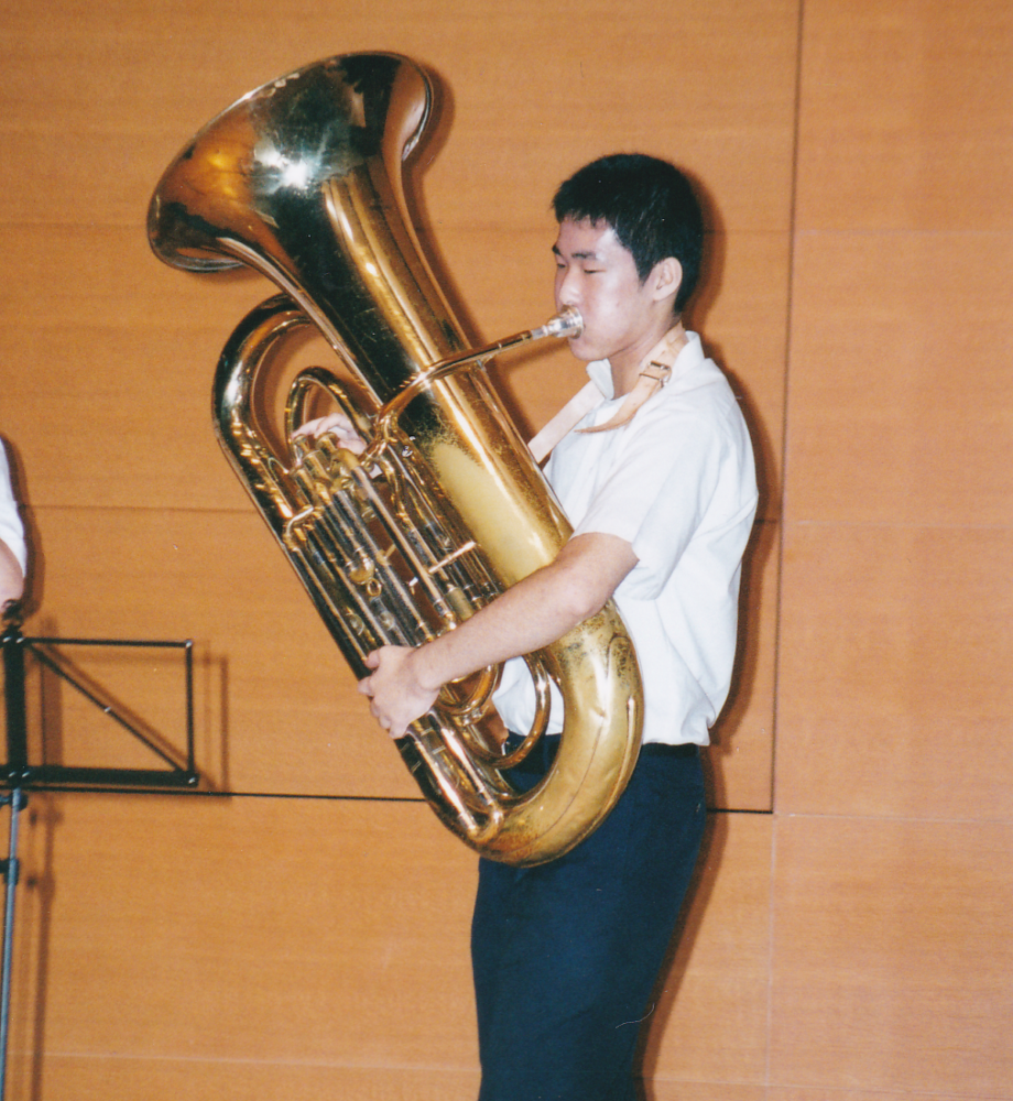 上半身ほどの大きさのある楽器を吹き、演奏する学生時代の吉田先生