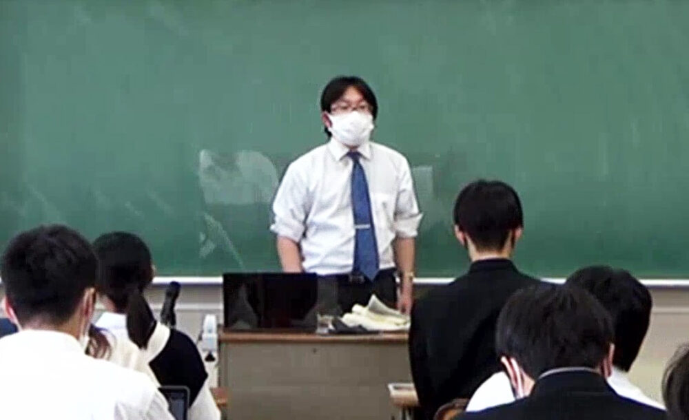 黒板の前で生徒に授業をする任田先生