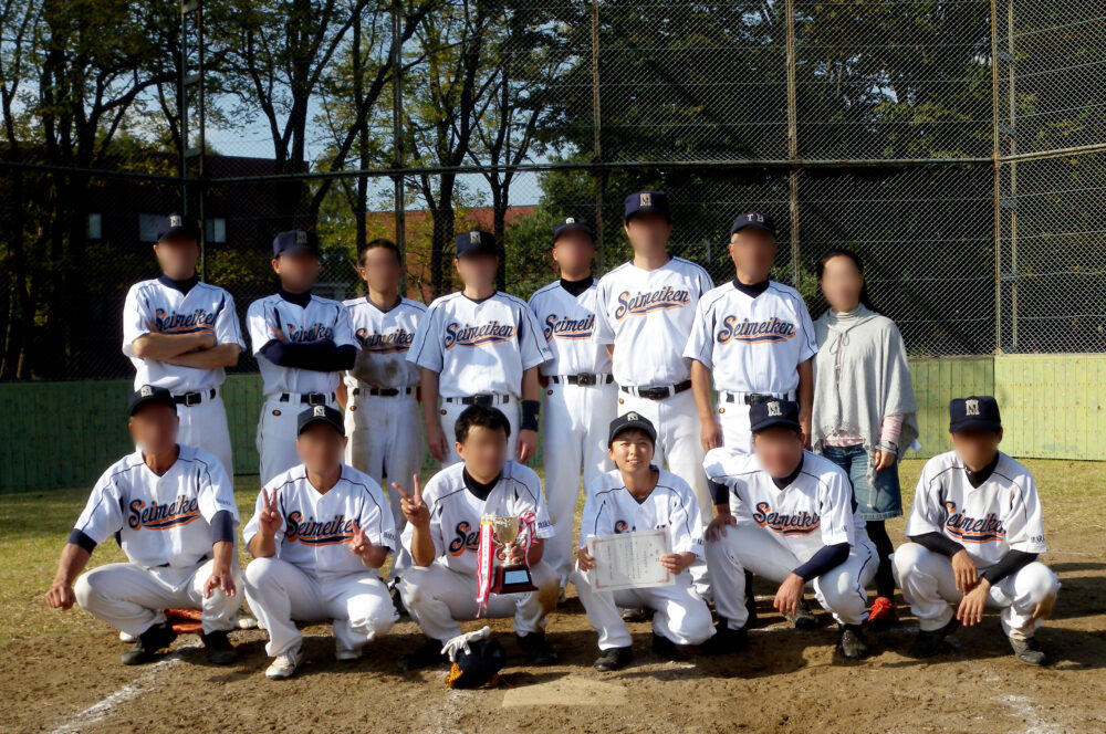 野球のユニフォームを着て、チームのみなさまと写真に写る貴嶋先生