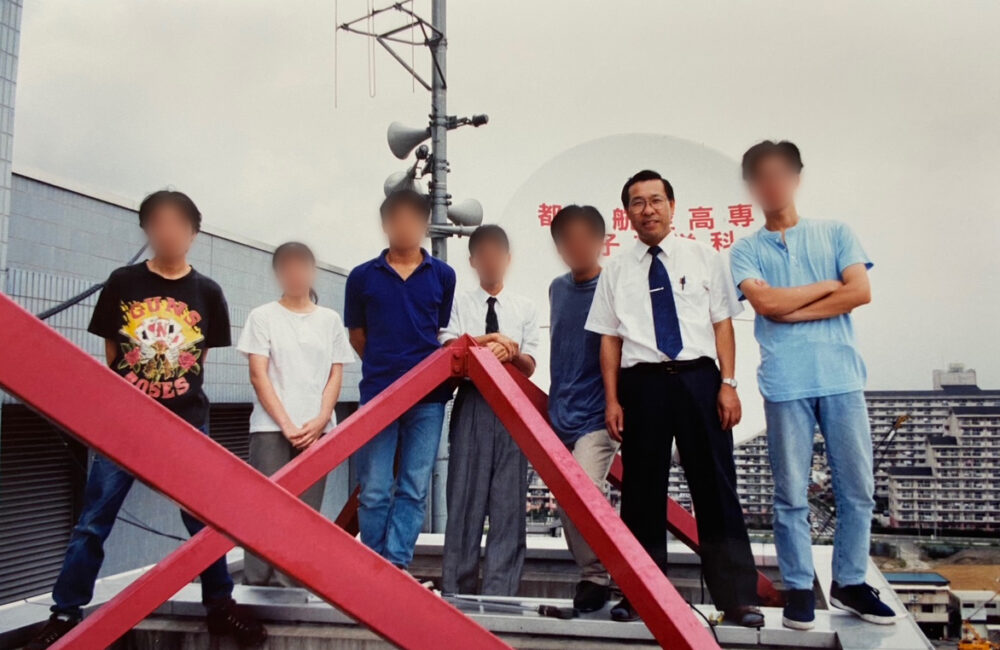 アンテナの前で、学生に囲まれて写真に写る島田先生