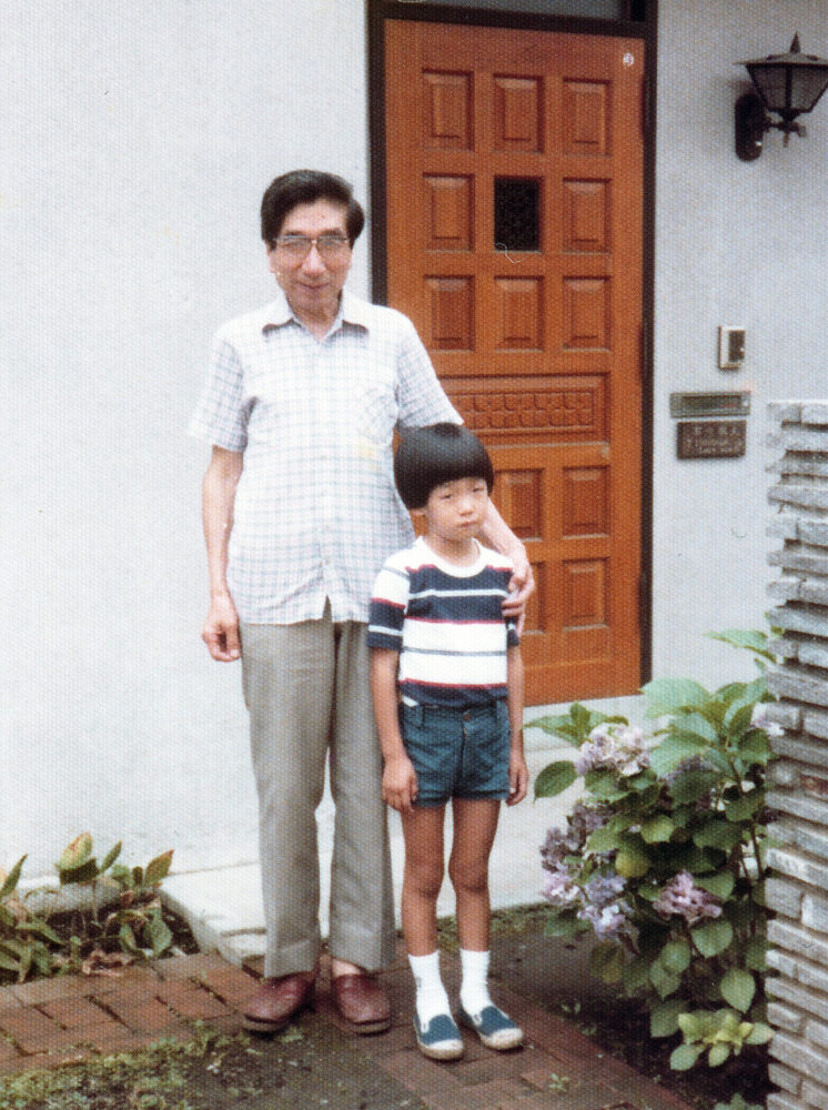 ご祖父様と、建物の入り口で写真に写る飯島先生