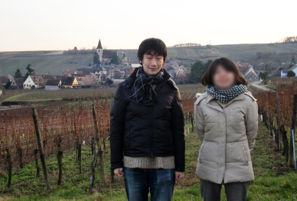 フランスののどかな田舎の風景の中、写真に写る水野先生と奥さま