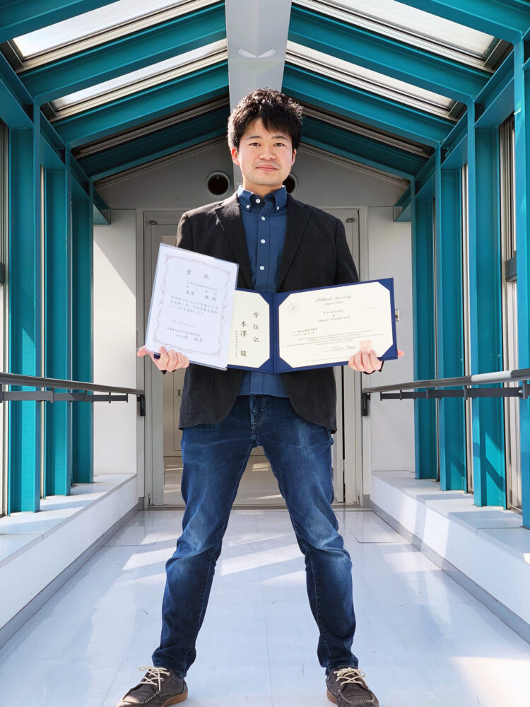 学位記と賞状を持ち写真に写る木澤さん