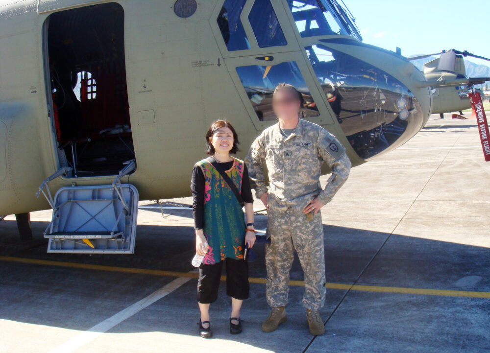 ヘリコプターの前で陸軍の方とともに写真に写る横田先生