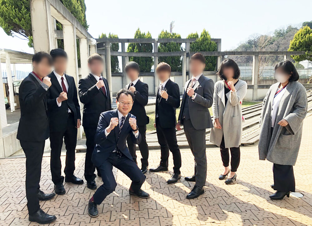 拳を握り、外で学生とともに写真に写る増田先生