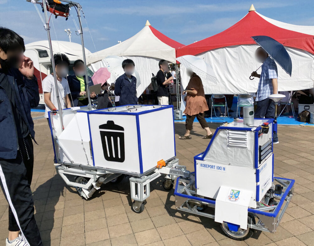ゴミ箱とミストカーテン機能が備わった台車を牽引する自律移動ロボット