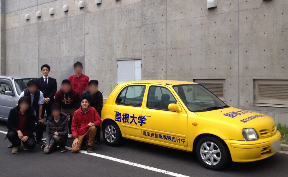 黄色いコンバートEVと一緒に写真に写る七森先生と山本先生