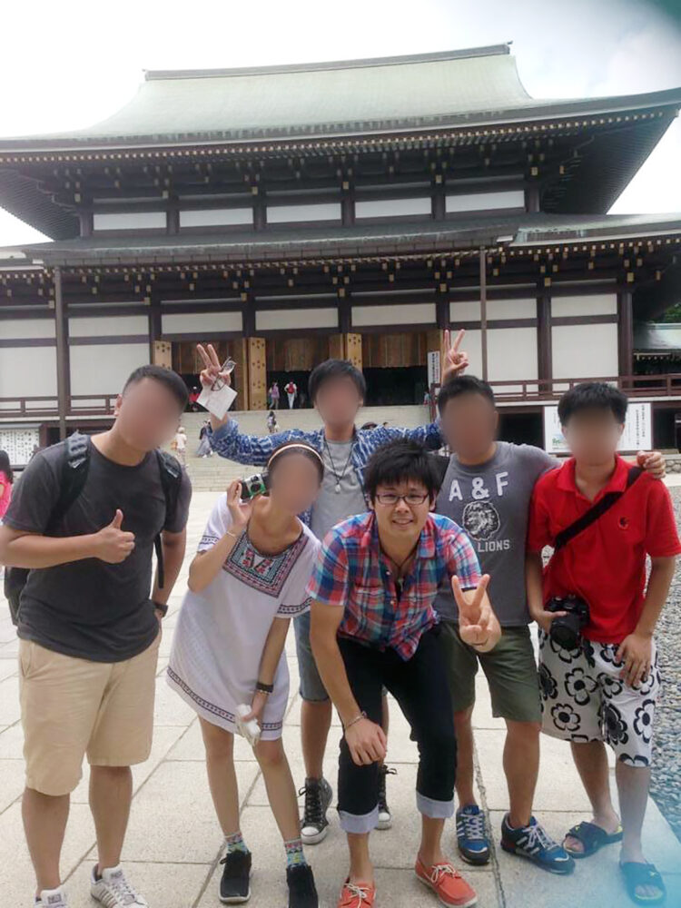 お寺の前で台湾からの留学生と並んで写真に写る大里先生
