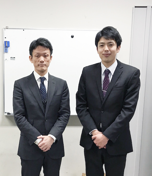 スーツを着て山本先生と一緒に写真に写る七森先生