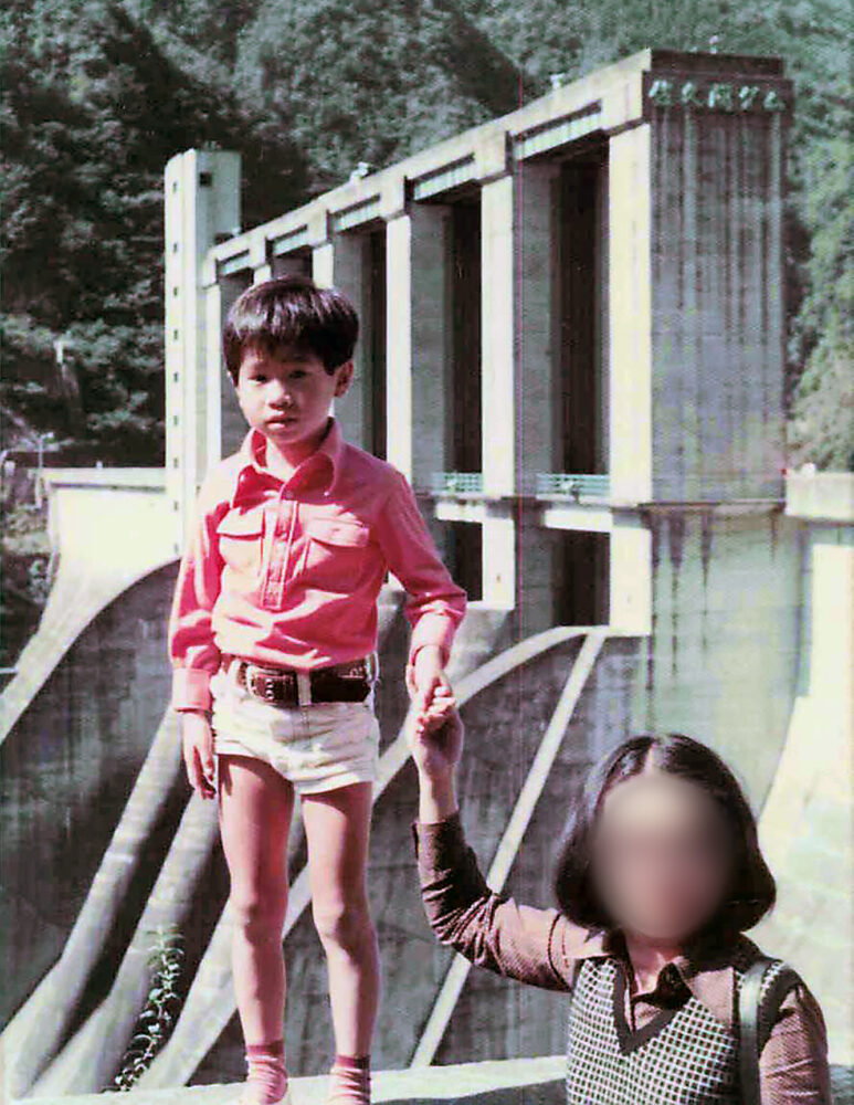 ダムの前でお母さまと手をつなぐ冨田先生