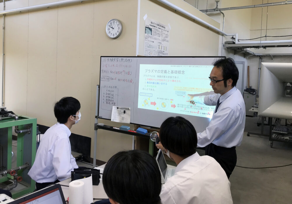 ホワイトボードにスライドを映して学生に解説する中村先生