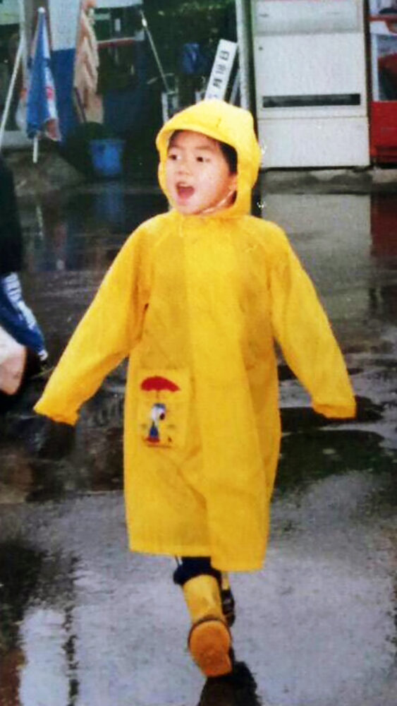 黄色いレインコートを着て歩く幼き日の小林先生