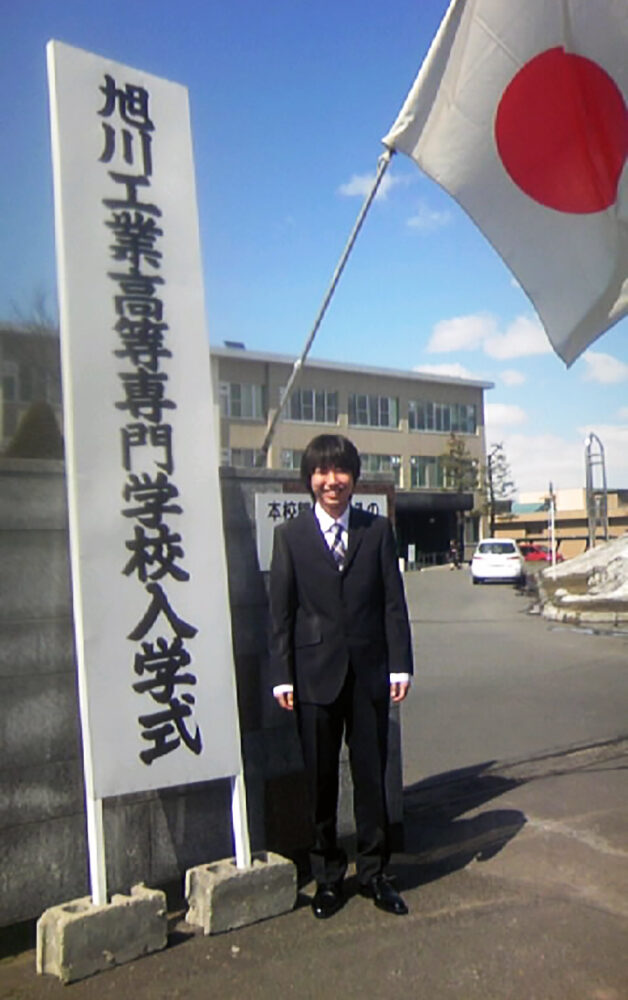 入学式に学校の門の前で写真に写る髙橋さん