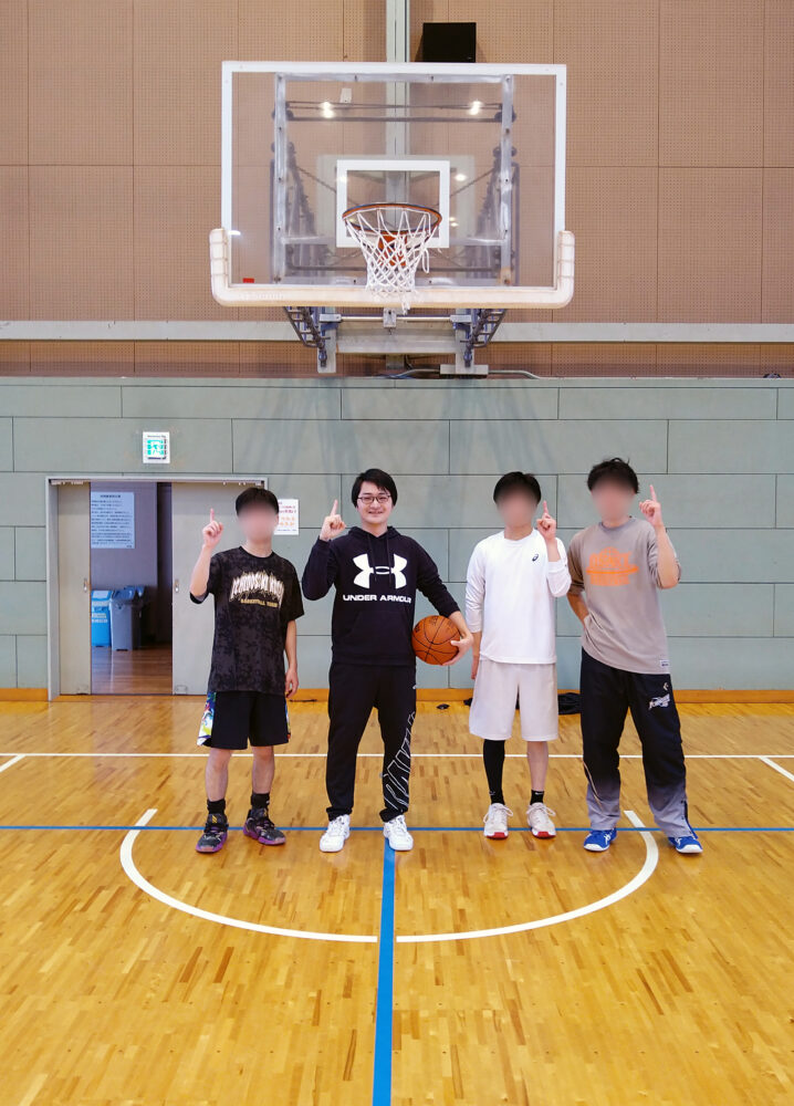バスケ部の皆さまと体育館で写真に写る川合先生