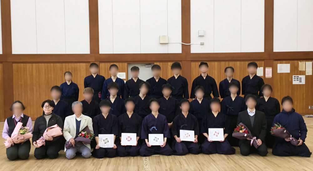 剣道の道着を着た学生たちと写真に写る大塩先生