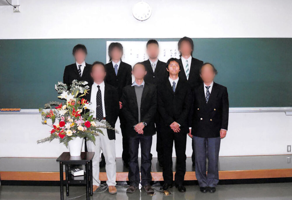 黒板の前で写真に写る吉田先生