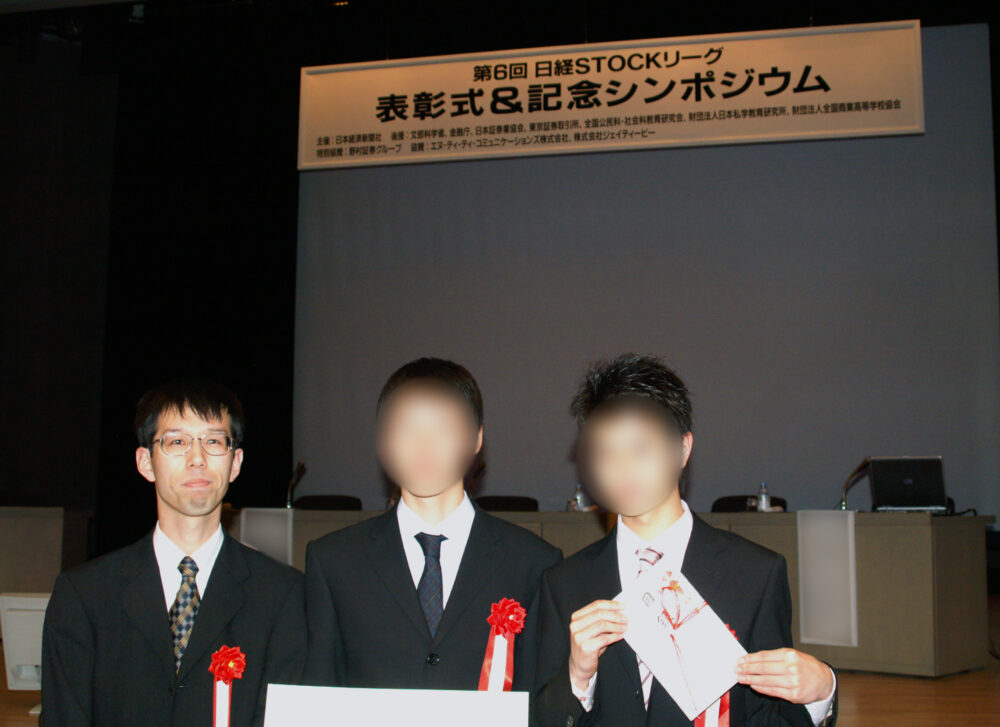 シンポジウムの会場にて、学生たちと写真に写る佐藤先生