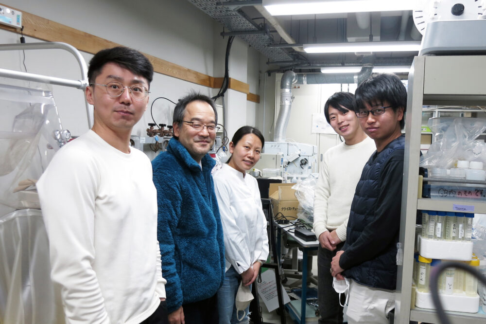 実験室にて学生さんと写真に写る髙橋先生