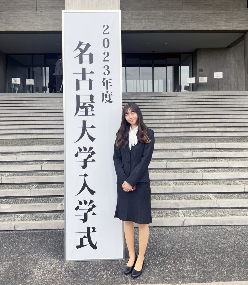 「名古屋大学入学式」というパネルのそばで写真に写る山田さん