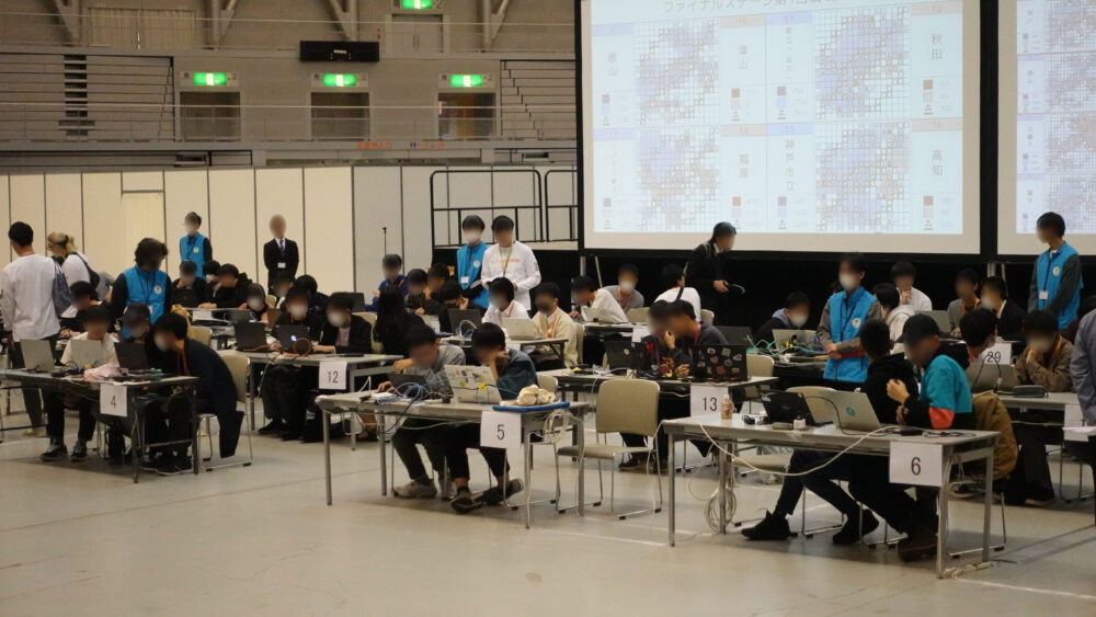 対決でチームごとに2人もしくは3人がテーブルに座り、パソコンを開いてゲームを行っている様子。