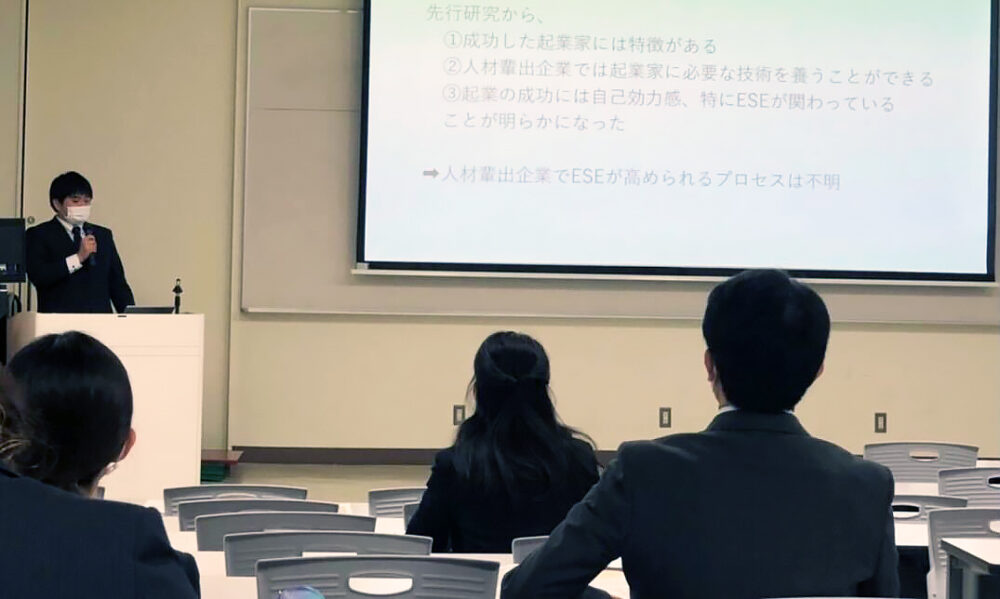 卒業研究について発表中の黒澤さん。演台からパワーポイントとスクリーンを用いて発表する様子。