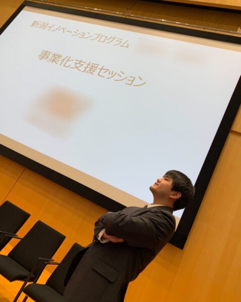 新潟大学で起業イベントに参加したときの黒澤さん。スクリーンとパワーポイントを使って発表する様子。