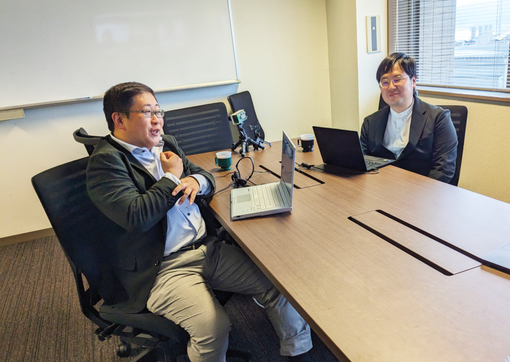 取材の様子。前田先生と安川先生が机をはさんで向かい合わせに座っている。前田先生が話している様子を安川先生が見ている。