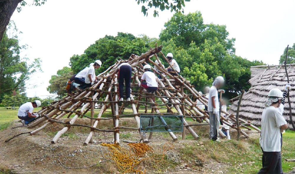 大勢で協力して竪穴住居復元作業を行っている様子