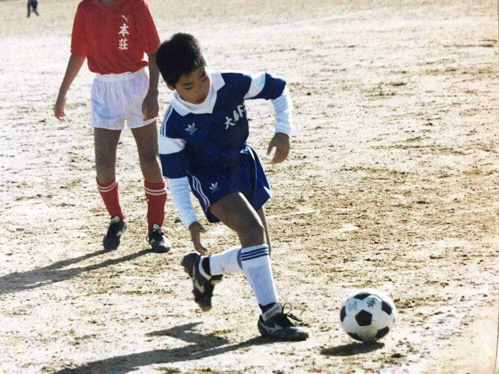 ユニフォームを着てサッカーをしている小学生時代の津田興利さん