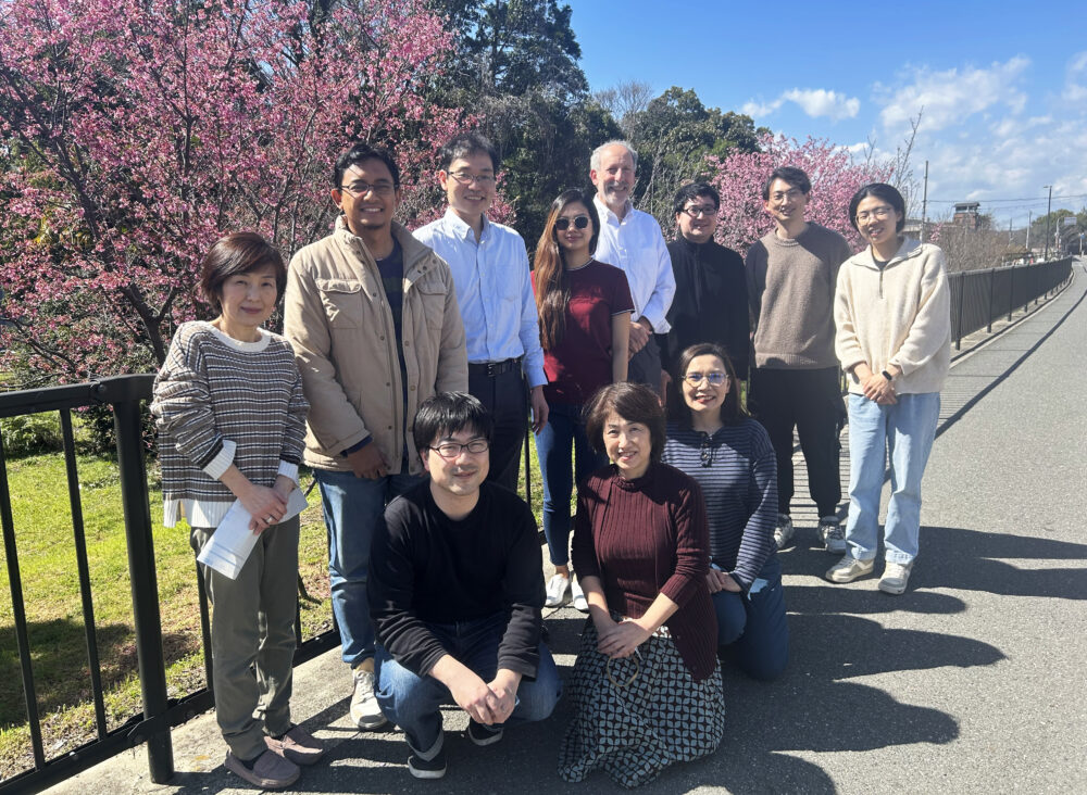 歩道で大学の研究室の皆さまと写真に写る佐山先生